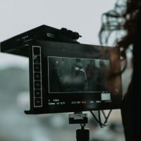 A close-up of professional filming equipment capturing a scene outdoors.