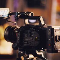 A modern video camera on a tripod with a small screen, perfect for filmmaking and video production.