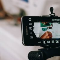Smartphone on tripod capturing person writing on paper, showing content creation process.